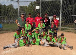 A photo of a youth baseball team celebrating with their championship medals, taken at home plate